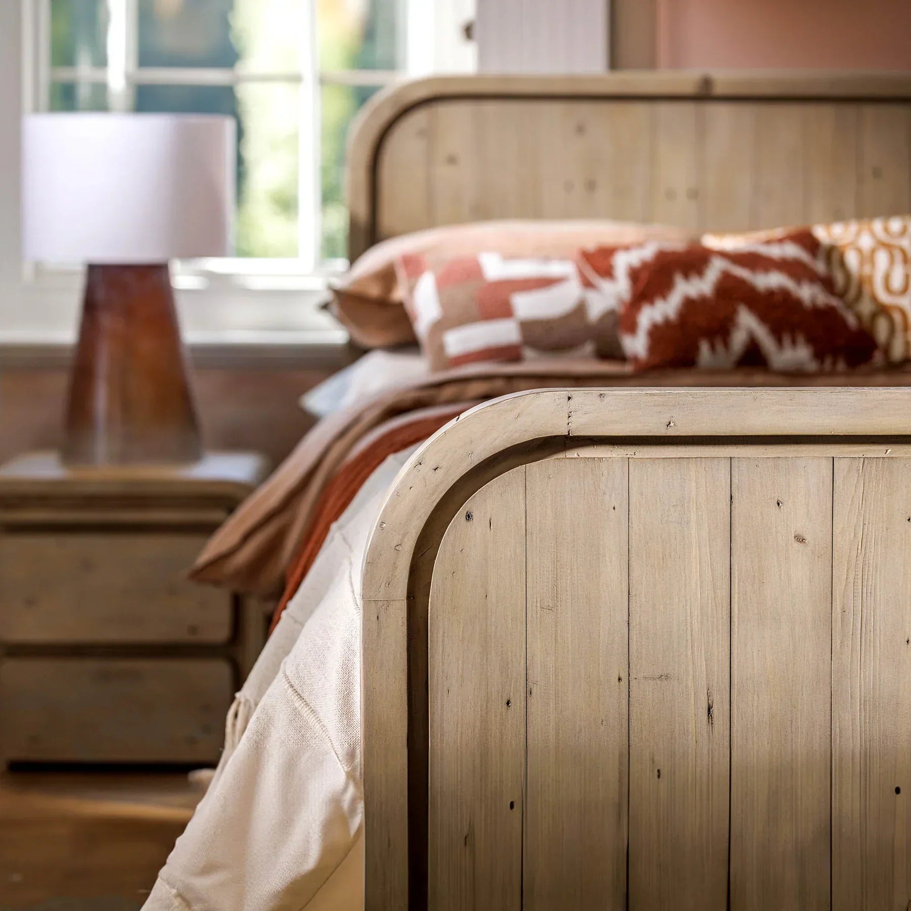 Perspective detail shot of the headboard styled with warm, patterned pillows and a modern bedside lamp