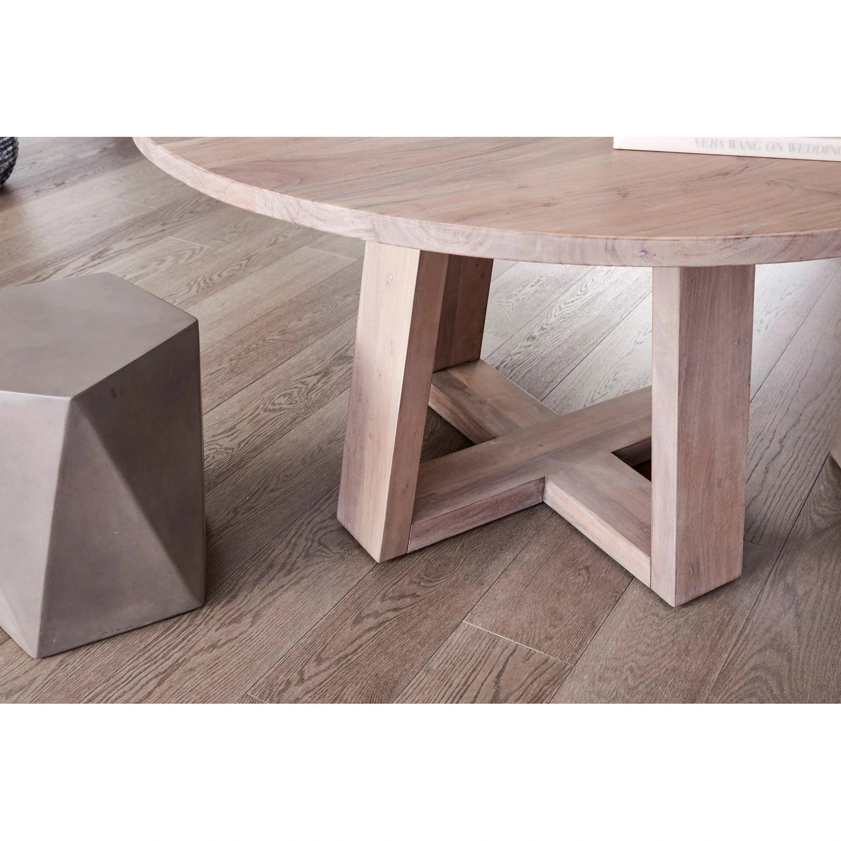 Front view of the Tanya round dining table in a light grey wood finish featuring a minimalist circular top and a sturdy cross-base design