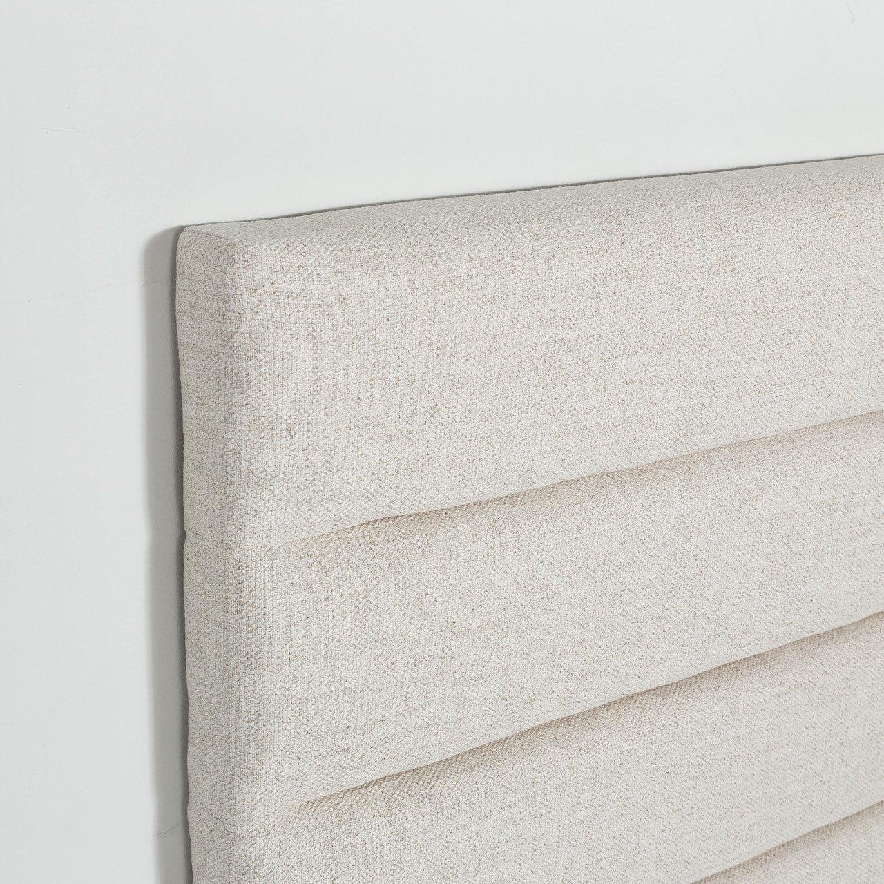 Close-up shot highlighting the soft tactile texture of the cream upholstery and the precision of the horizontal tufted seams
