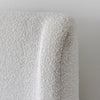 Close-up shot focusing on the soft radius of the wingback headboard and the rich tactile bouclé fabric grain