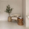 Side-by-side view of the table in a minimalist entryway corner next to a modern armchair and indoor plant