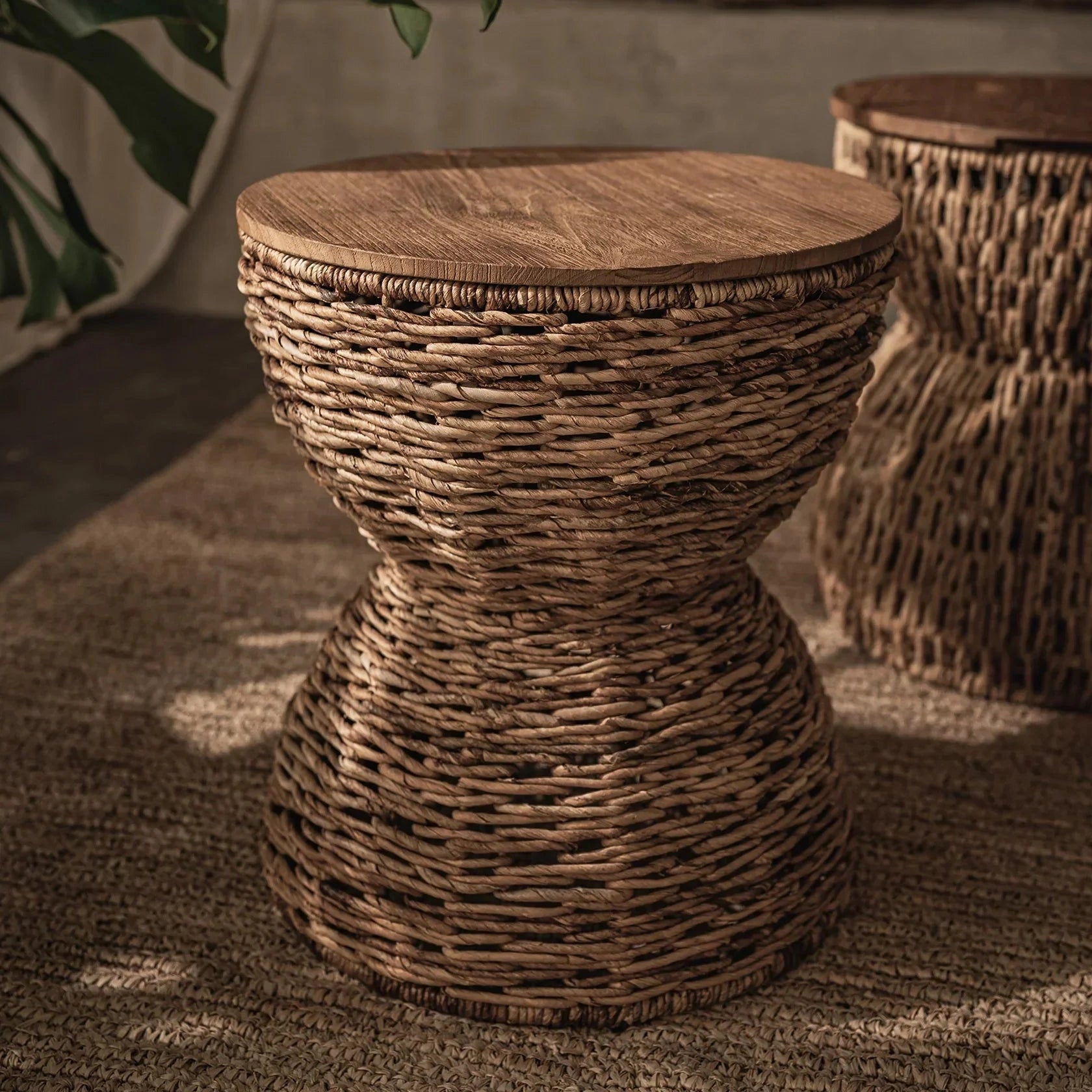 Front view of the D-Bodhi Rebana Alto side table featuring a hand-woven natural rattan hourglass base and a smooth circular reclaimed wood top