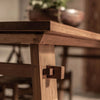 Extreme close-up focusing on the expert traditional joinery and exposed wood tenon of the artisan table frame