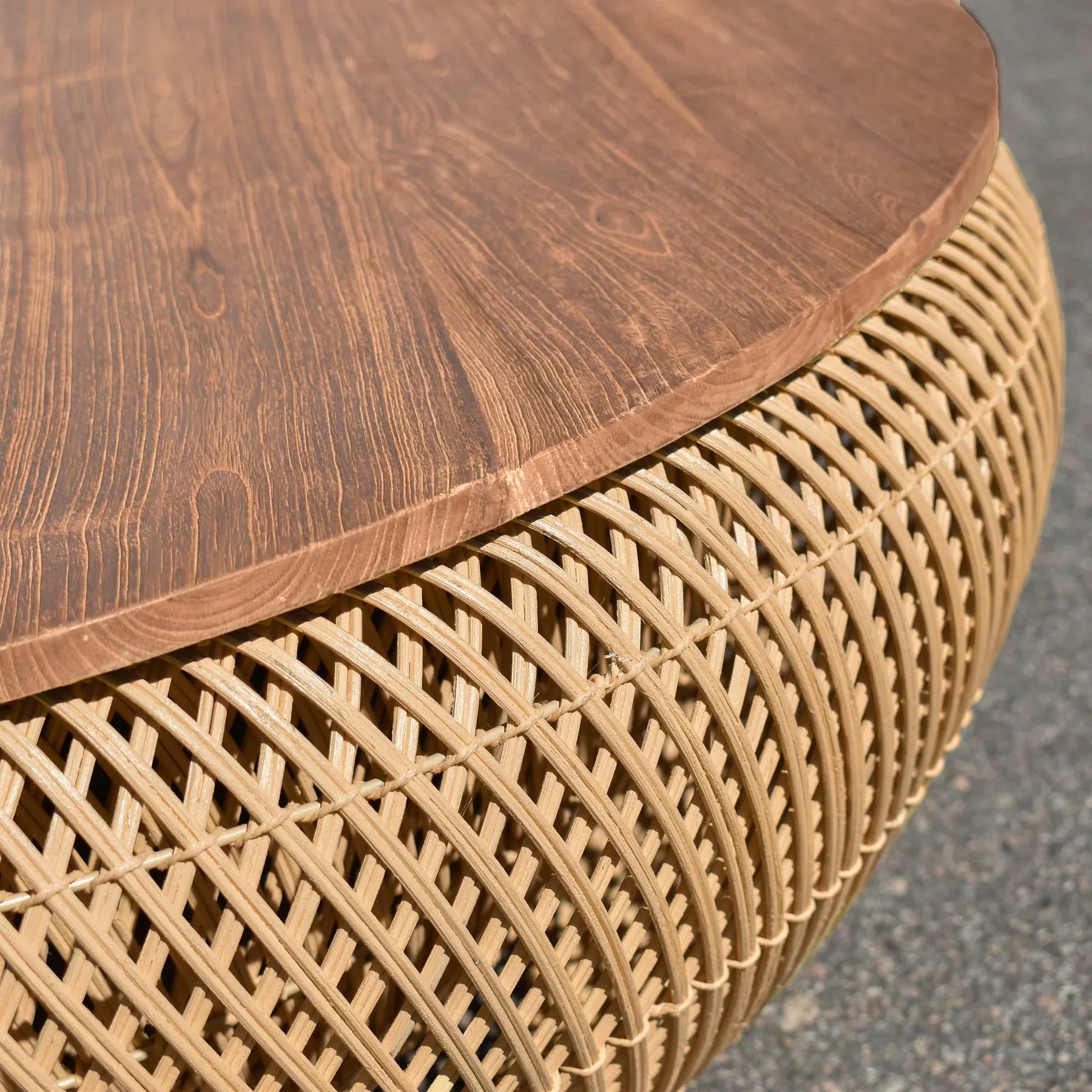 Front view of the large D-Bodhi Wave coffee table featuring a rounded woven abaca base in a natural finish with a solid recycled wood tabletop
