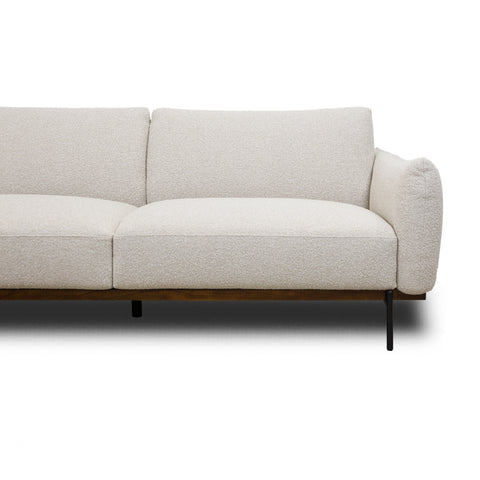 Front view of Idony sofa in beige fabric with curved arms, wooden base, and black metal legs