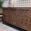 Close-up lifestyle shot featuring the carved sideboard styled in a warm eclectic environment with natural greenery