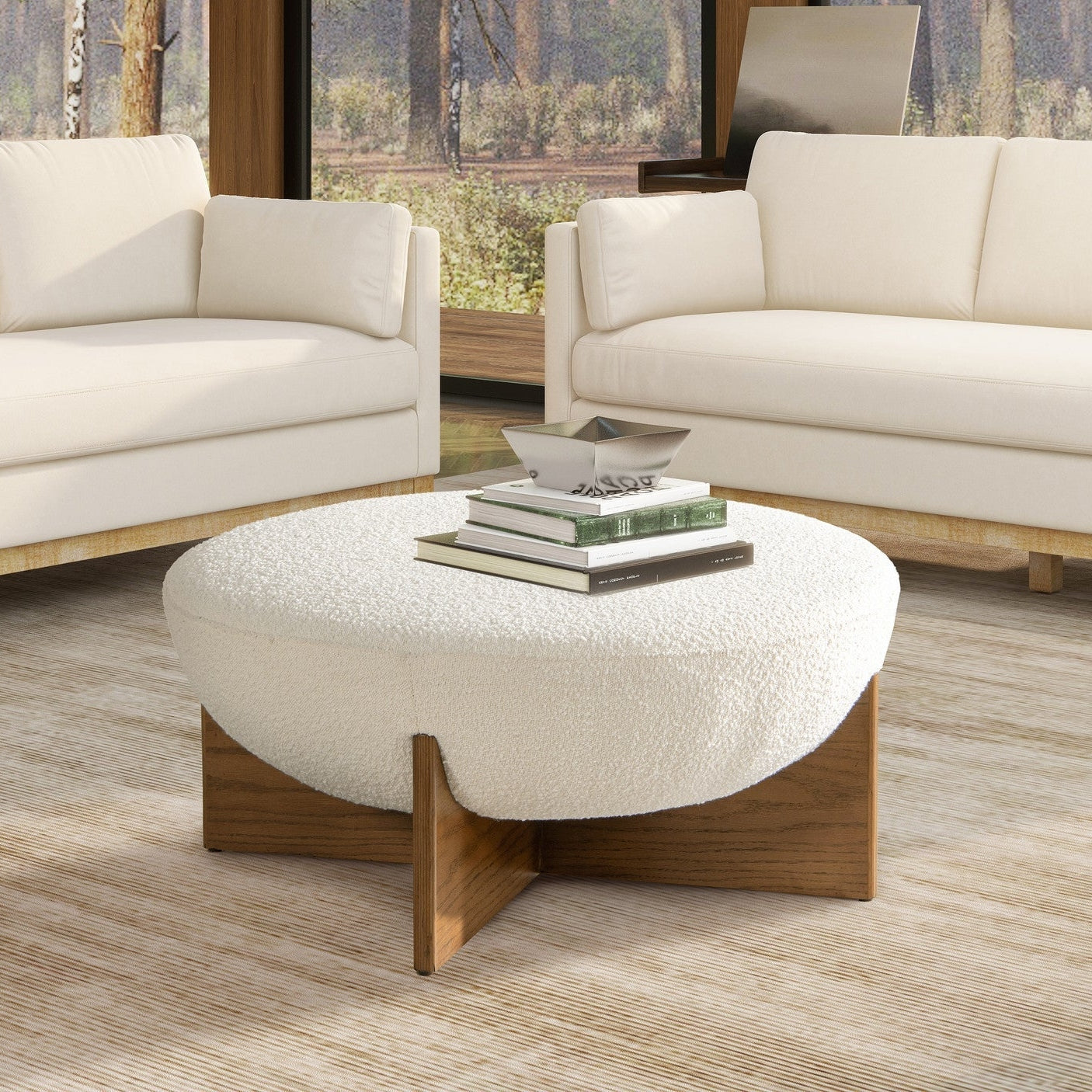Front view of the Elara ottoman featuring a white bouclé bowl-shaped seat and a natural wood cross-base frame