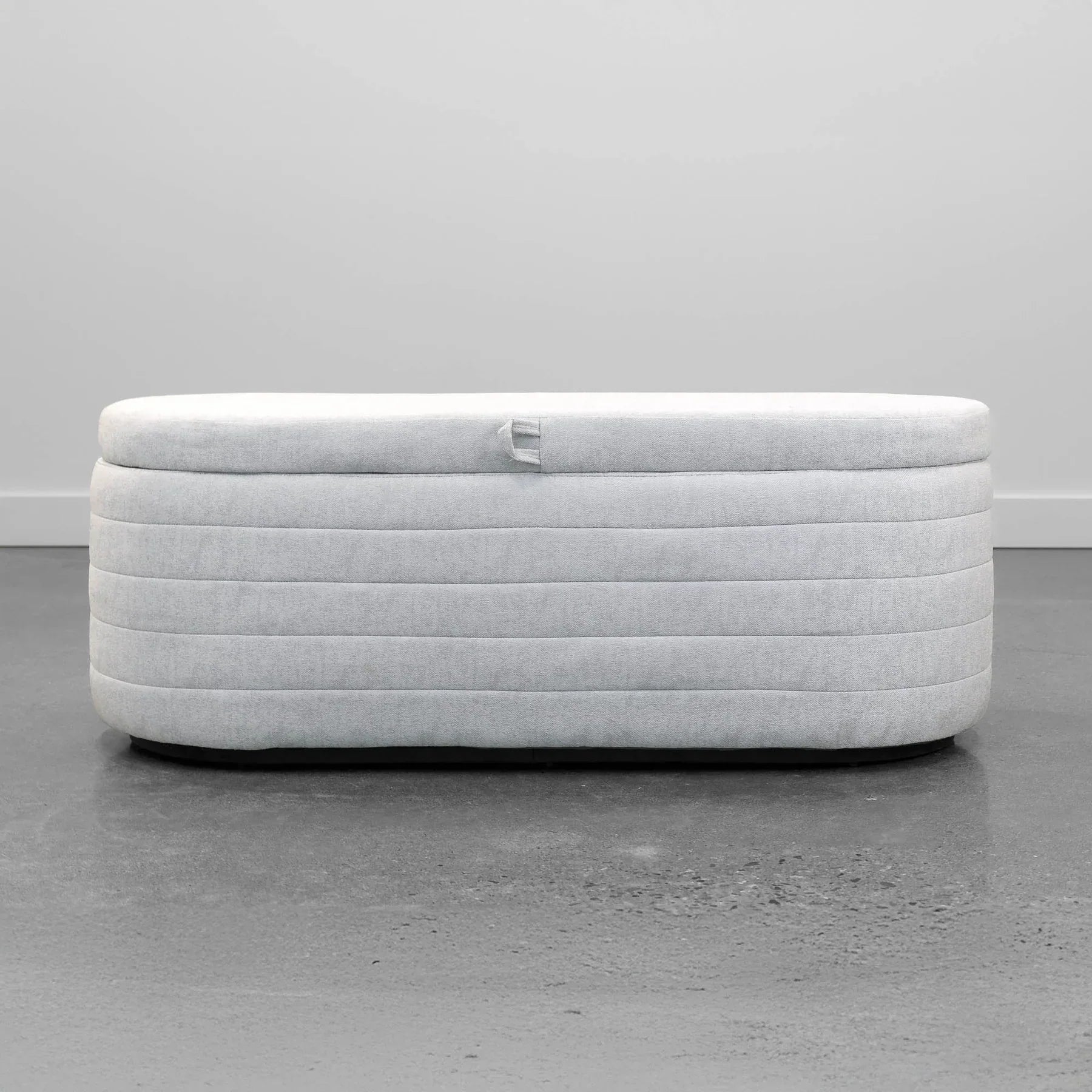 Front view of the Elio oval storage bench featuring platinum gray fabric and modern horizontal channel tufting