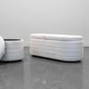 Studio lifestyle shot showcasing the Elio platinum storage bench alongside the matching round storage ottoman