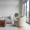 The Estelle rounded chair styled in a bright, minimalist living room next to a white modular sofa.