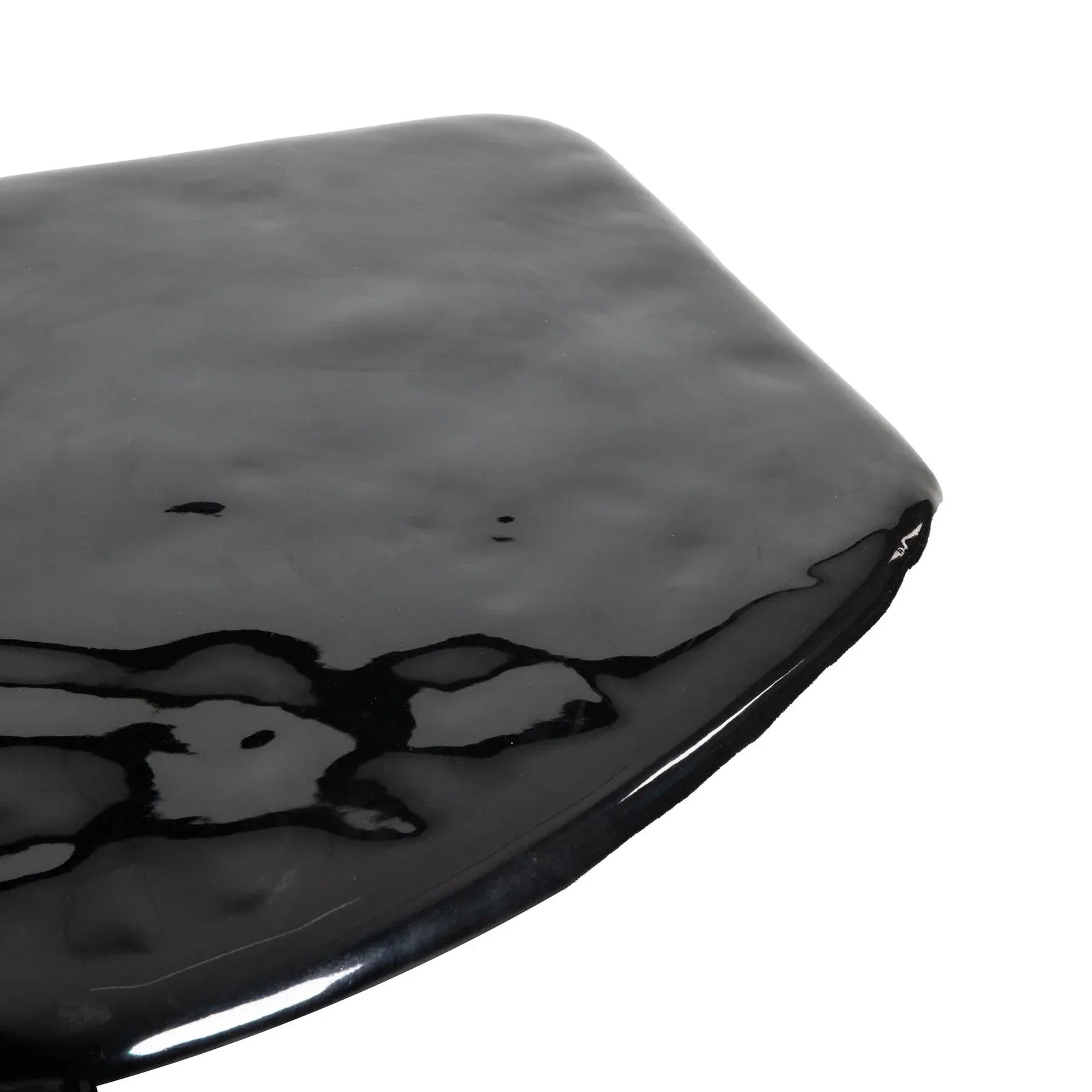 Macro close-up focusing on the liquid-like reflective quality and subtle organic ripples of the high-shine black tabletop surface