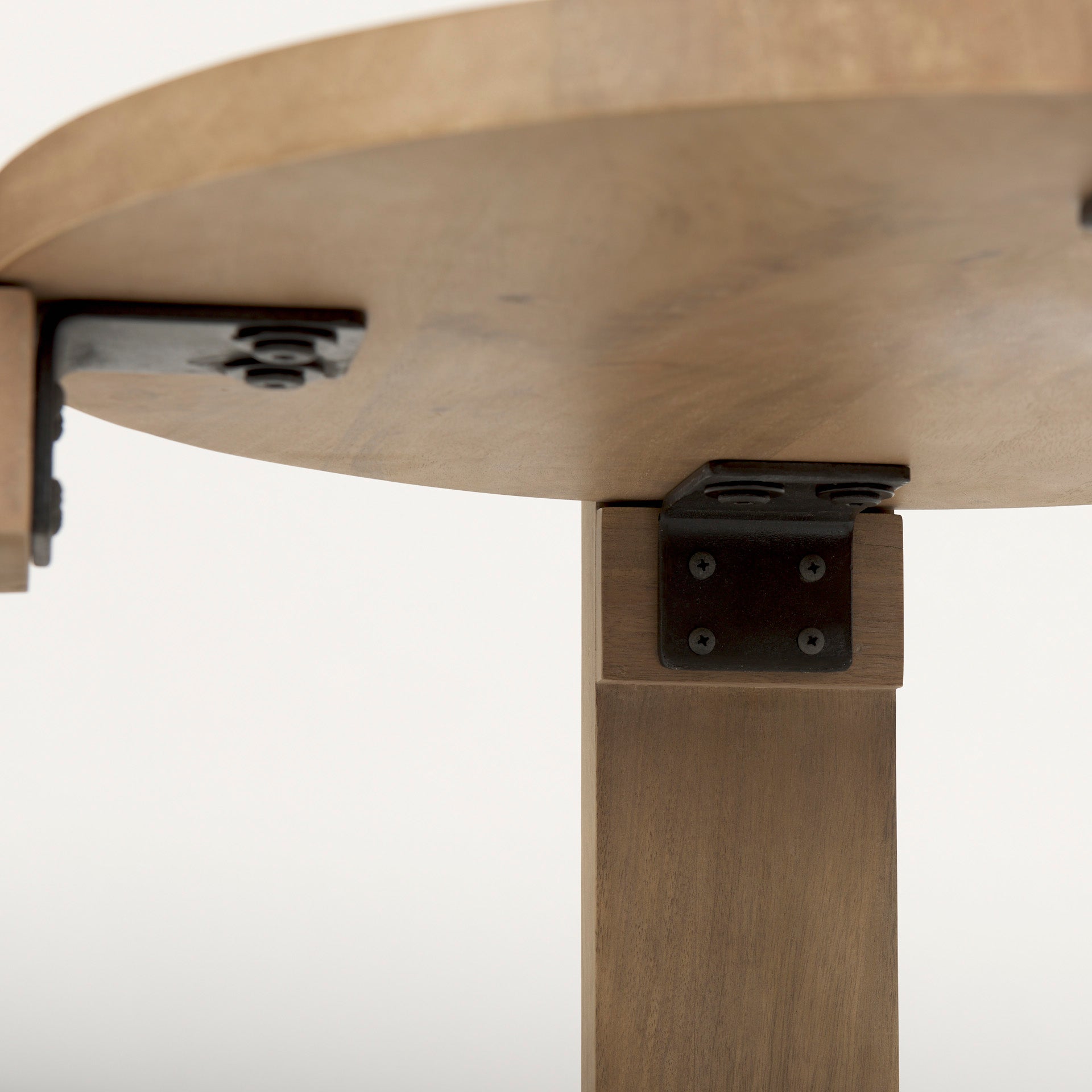 Underside view of the table showing the black metal brackets and hardware used to secure the solid wood legs to the tabletop
