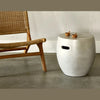 Lifestyle view of the fiber cement table used as an accent piece next to a woven outdoor lounge chair in a modern patio setting