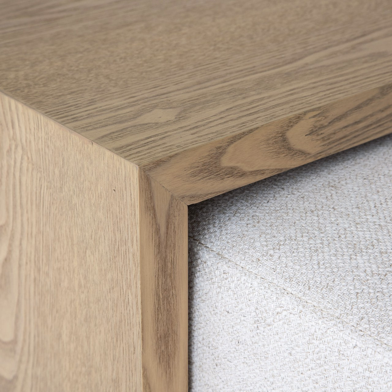 Front view of the Forest coffee ottoman featuring a cream upholstered rectangular bench with a nested blonde oak waterfall table