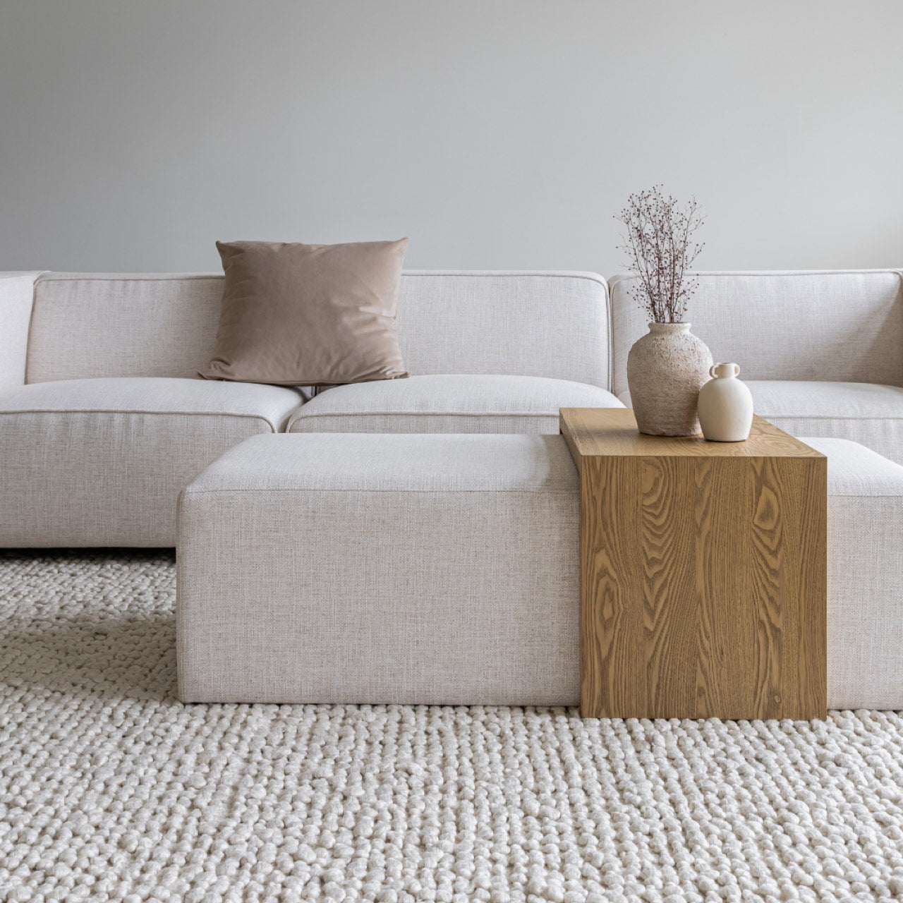 Front view of the Forest coffee ottoman featuring a cream upholstered rectangular bench with a nested blonde oak waterfall table