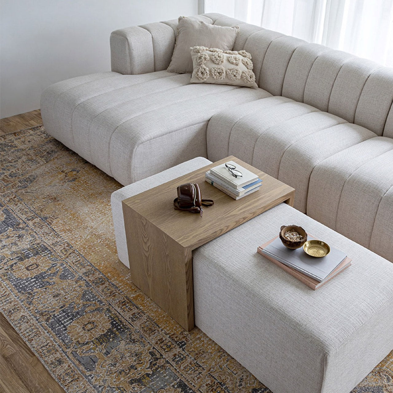 Front view of the Forest coffee ottoman featuring a cream upholstered rectangular bench with a nested blonde oak waterfall table