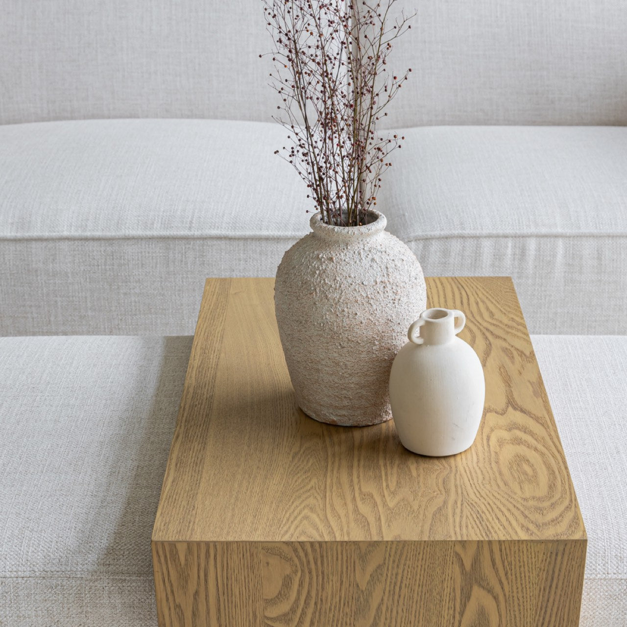 Front view of the Forest coffee ottoman featuring a cream upholstered rectangular bench with a nested blonde oak waterfall table