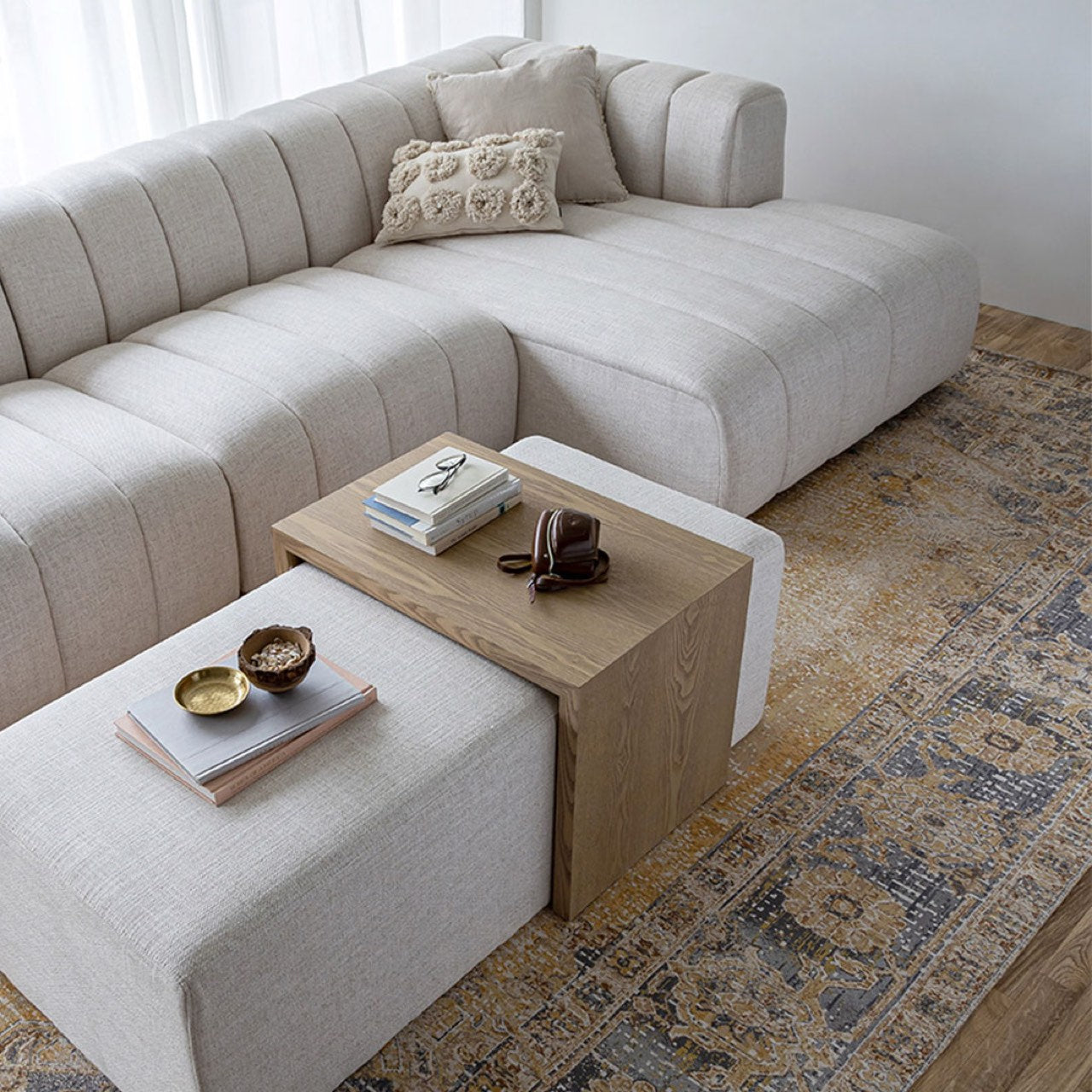 Front view of the Forest coffee ottoman featuring a cream upholstered rectangular bench with a nested blonde oak waterfall table