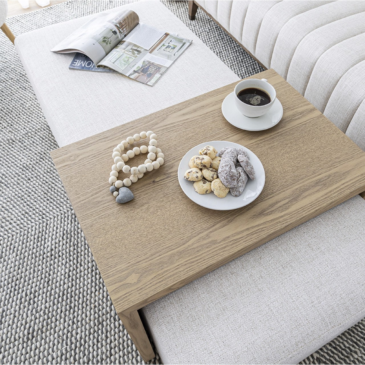 Front view of the Forest coffee ottoman featuring a cream upholstered rectangular bench with a nested blonde oak waterfall table