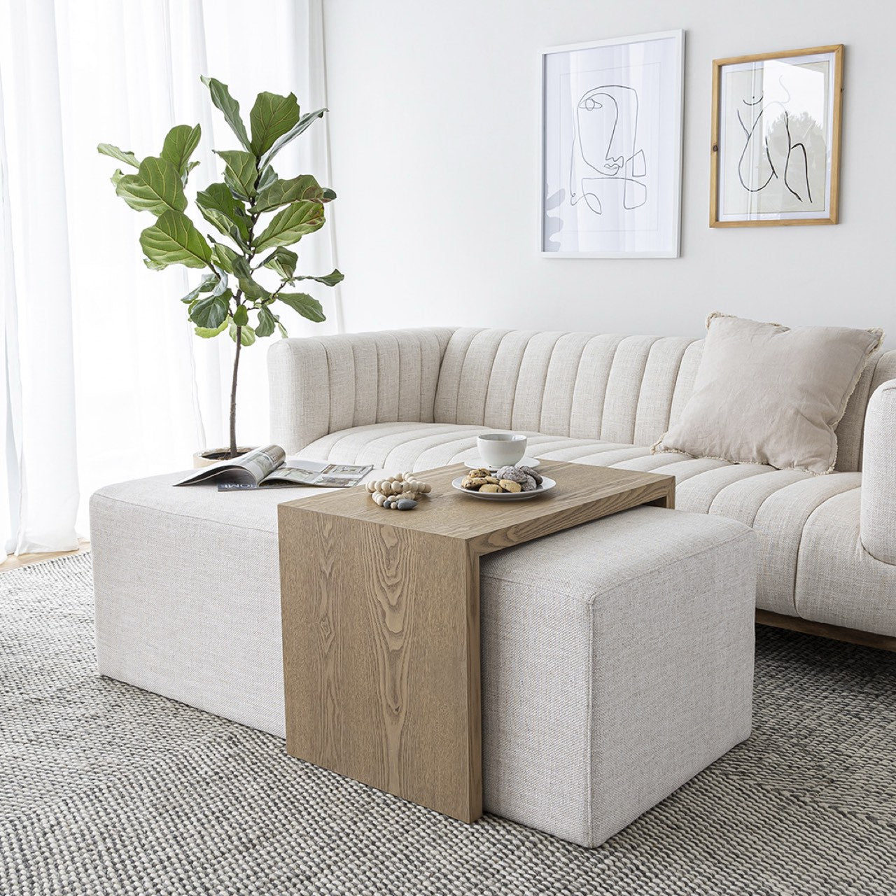 Front view of the Forest coffee ottoman featuring a cream upholstered rectangular bench with a nested blonde oak waterfall table