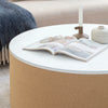 Close-up lifestyle view of the Fresco table styled with an open magazine and a candle in a bright contemporary setting