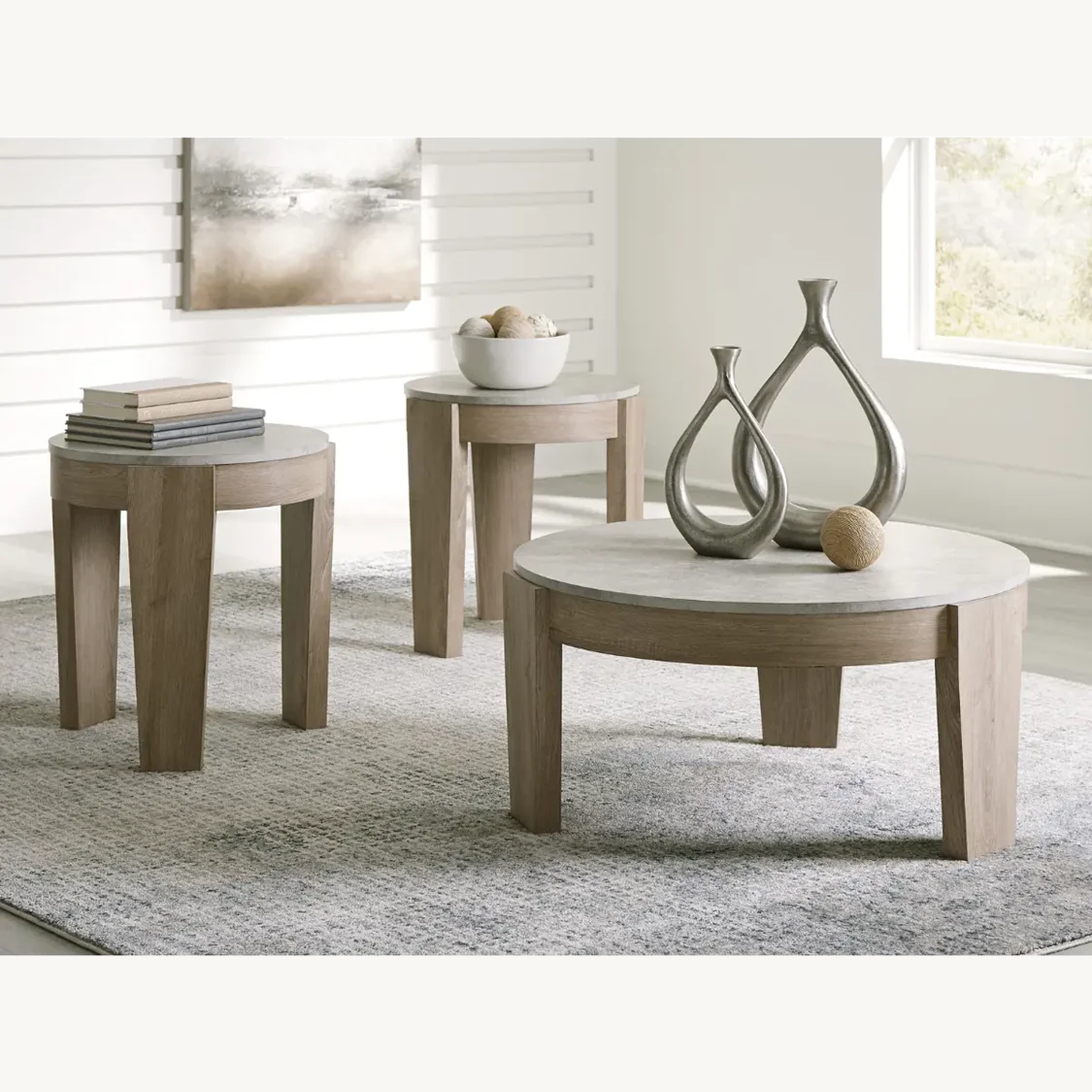 Lifestyle shot of the Guystone 3-piece occasional table set styled in a bright living room with decorative grey vases