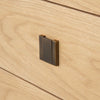 Macro detail shot focusing on the low-profile bronze square handle and the subtle natural wood grain of the oak surface