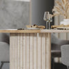 Detailed lifestyle shot showcasing the table's surface and ribbed pedestal base in a realistic dining room setting