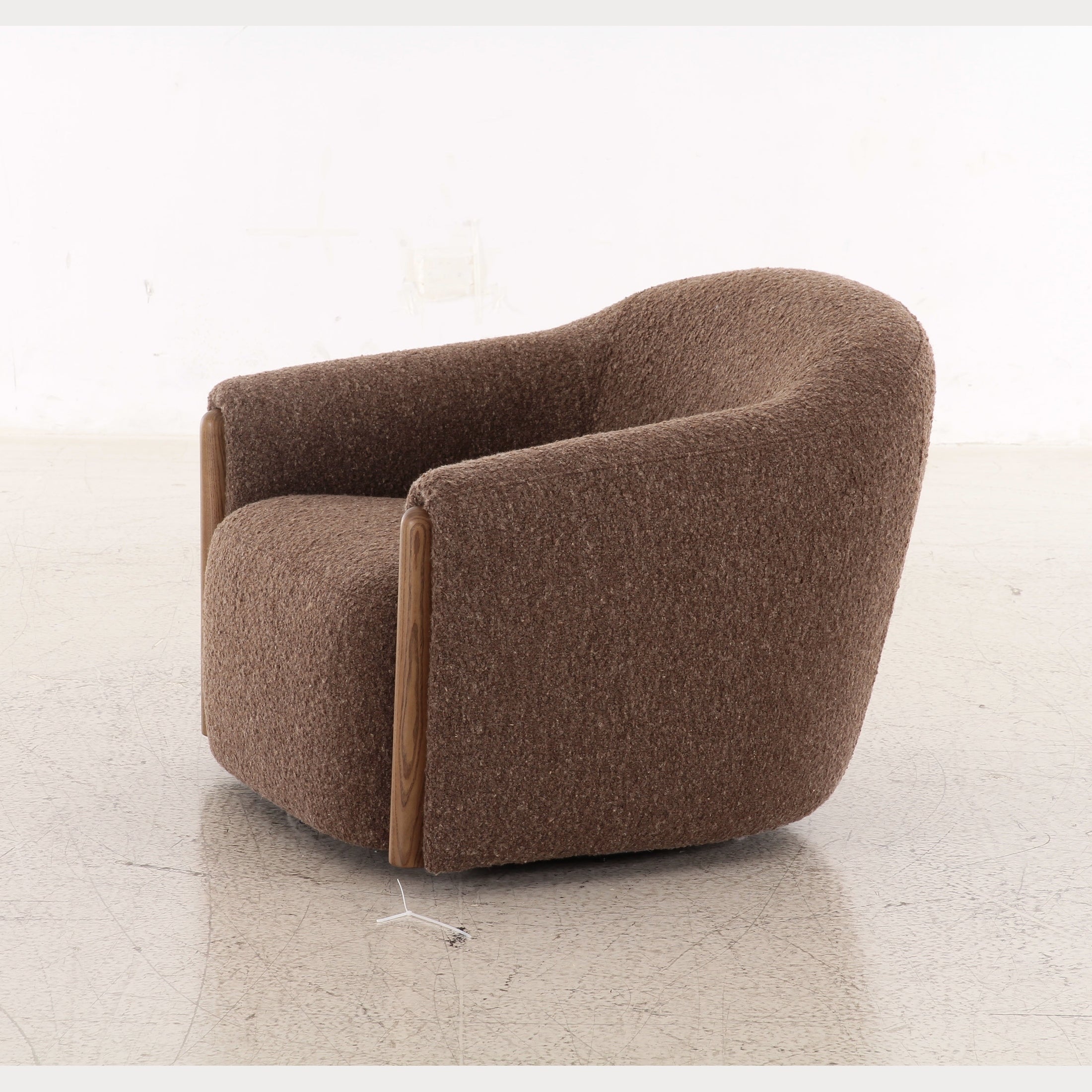Three-quarter perspective of the coffee brown Holmvik chair highlighting the thick sculptural legs and deep plush seat
