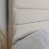 Close-up shot focusing on the high-quality sand fabric and the clean horizontal tufting lines of the cushioned headboard