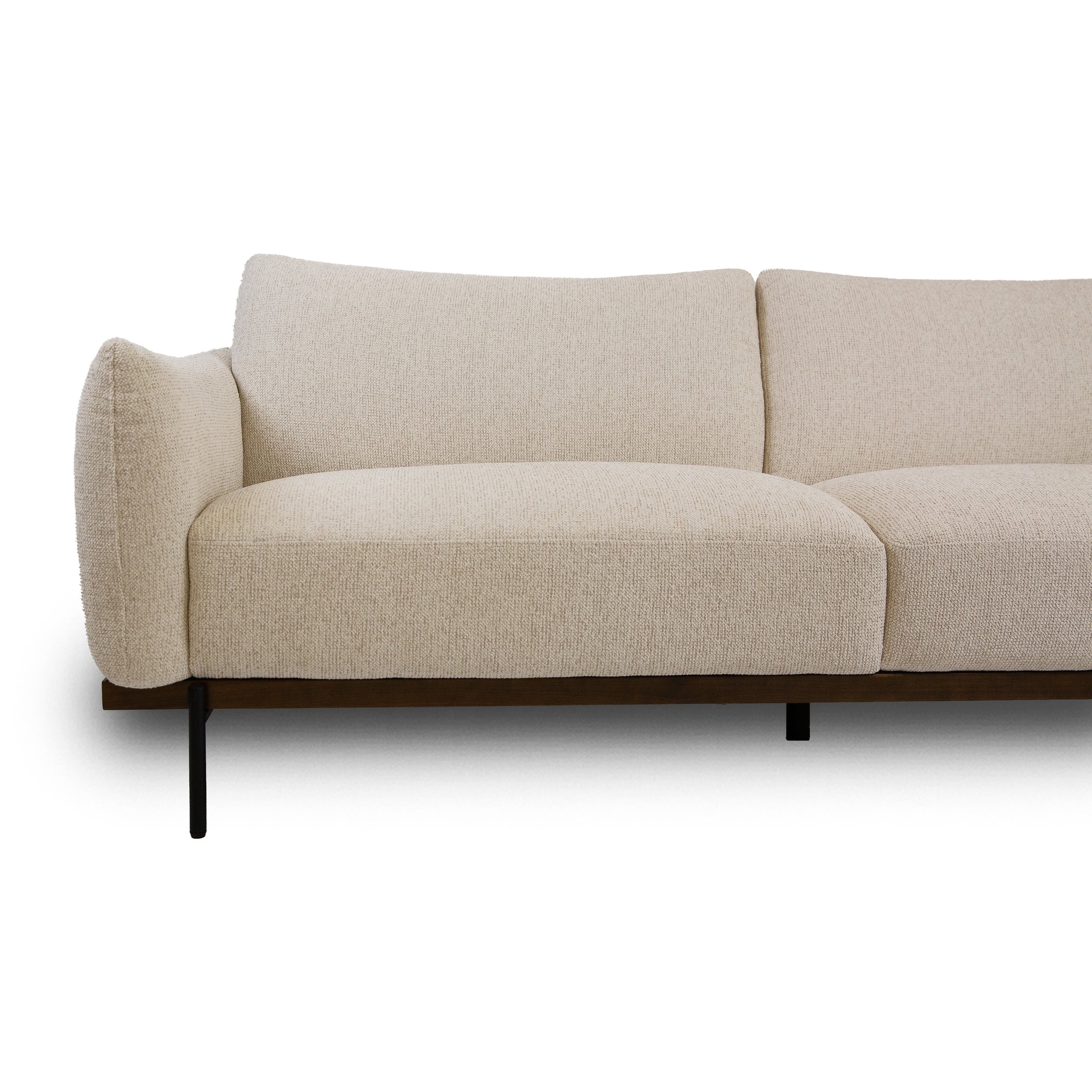 Close-up of Idony beige fabric sofa seat with curved armrest, wooden base, and black metal legs
