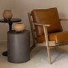 Lifestyle view of the dark grey concrete table styled next to a cognac leather armchair in a modern minimalist interior