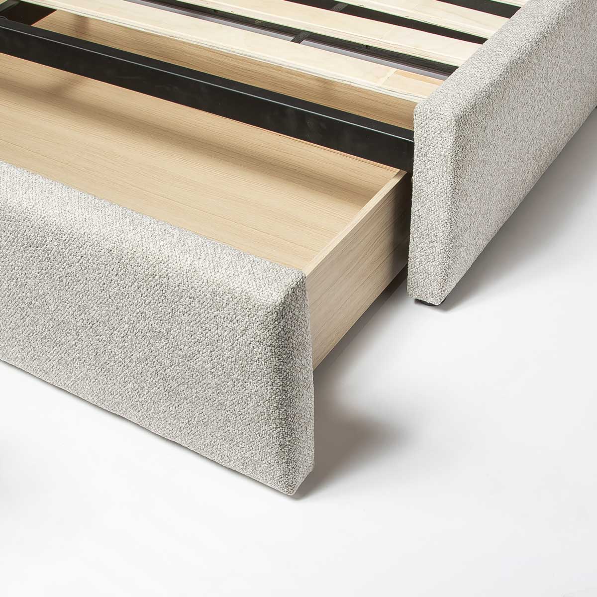 Side perspective view of the bed with a spacious integrated storage drawer extended to show internal wooden construction