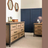 Side perspective lifestyle shot highlighting the dresser's substantial presence in a modern rustic bedroom setting