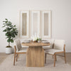 Studio lifestyle shot featuring the light brown oval table styled with neutral upholstered chairs in a bright minimalist dining room