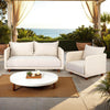 Lifestyle shot of the Ivory Coast Outdoor Loveseat and matching armchair styled on a patio with an ocean view