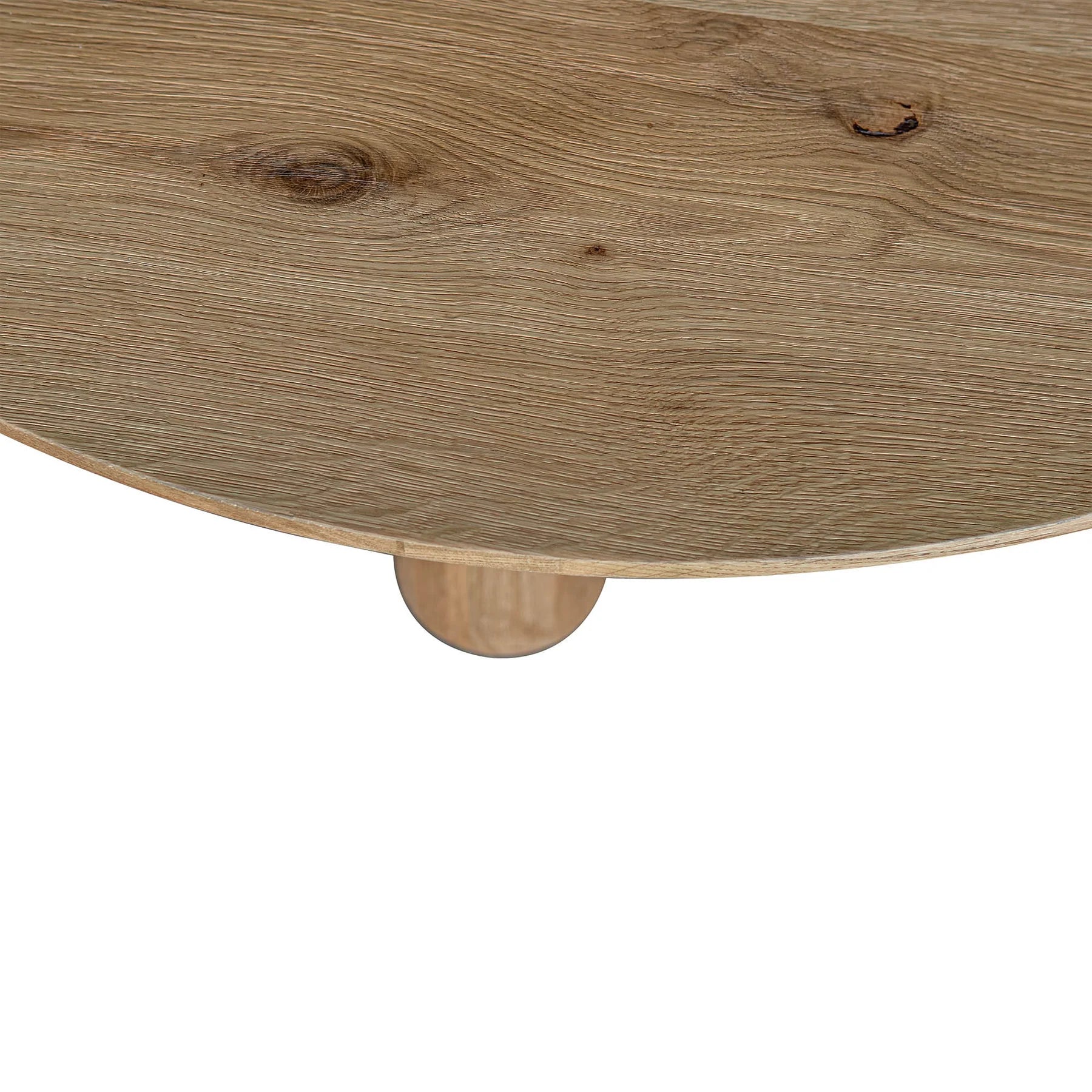 Three-quarter perspective view of the Jasper round dining table in a natural oak finish featuring three thick cylindrical pedestal legs