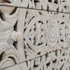 Macro detail shot focusing on the high-relief hand-carved floral motifs and the tactile white-washed wood texture