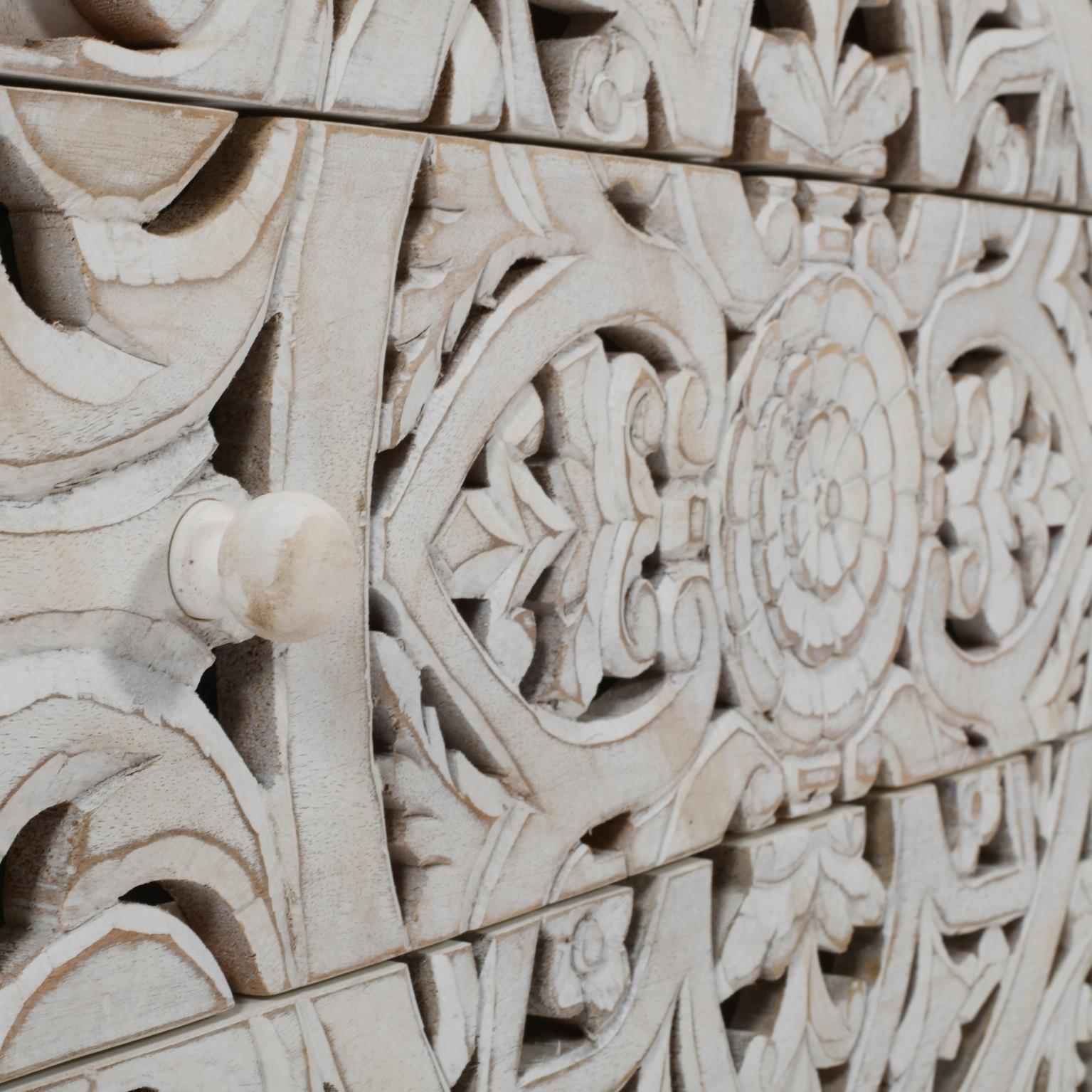 Macro detail shot focusing on the high-relief hand-carved floral motifs and the tactile white-washed wood texture