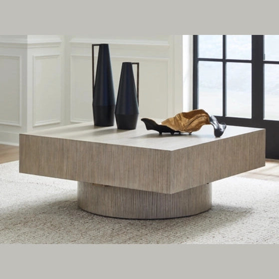 Front view of the Jorielyn coffee table featuring a square grey wood block top and a recessed cylindrical pedestal base