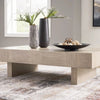 Lifestyle shot featuring the Jorlaina cocktail table styled with a black vase and decorative bowl in a modern living room