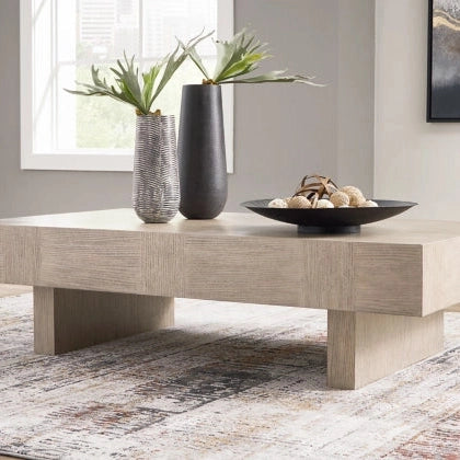 Lifestyle shot featuring the Jorlaina cocktail table styled with a black vase and decorative bowl in a modern living room