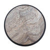 High-angle close-up highlighting the unique organic mineral veining and neutral beige tones of the round travertine surface