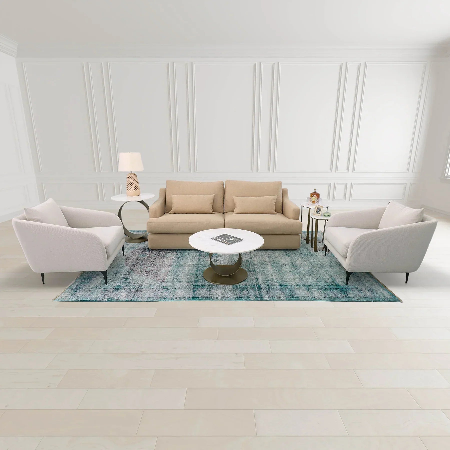 Wide lifestyle view of the Libra nesting tables paired with neutral armchairs and a blue patterned rug in a bright living room