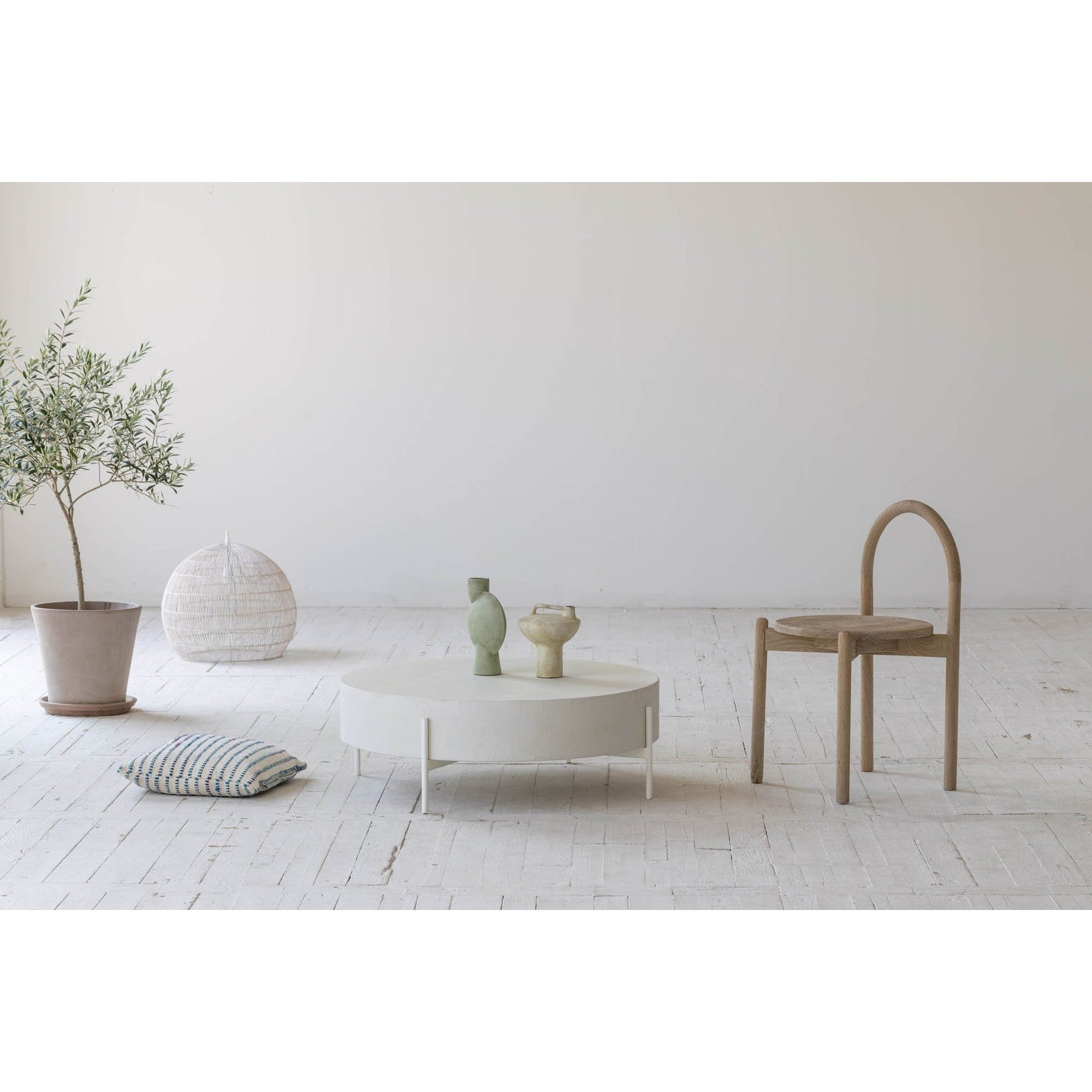 Front view of the Luna coffee table featuring a thick circular drum-style top in white concrete supported by a minimalist four-leg metal base
