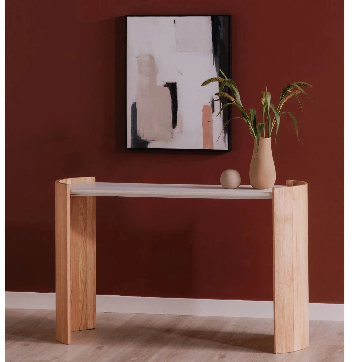 Lifestyle shot featuring the Dala console table set against a deep red accent wall styled with minimalist artwork and greenery
