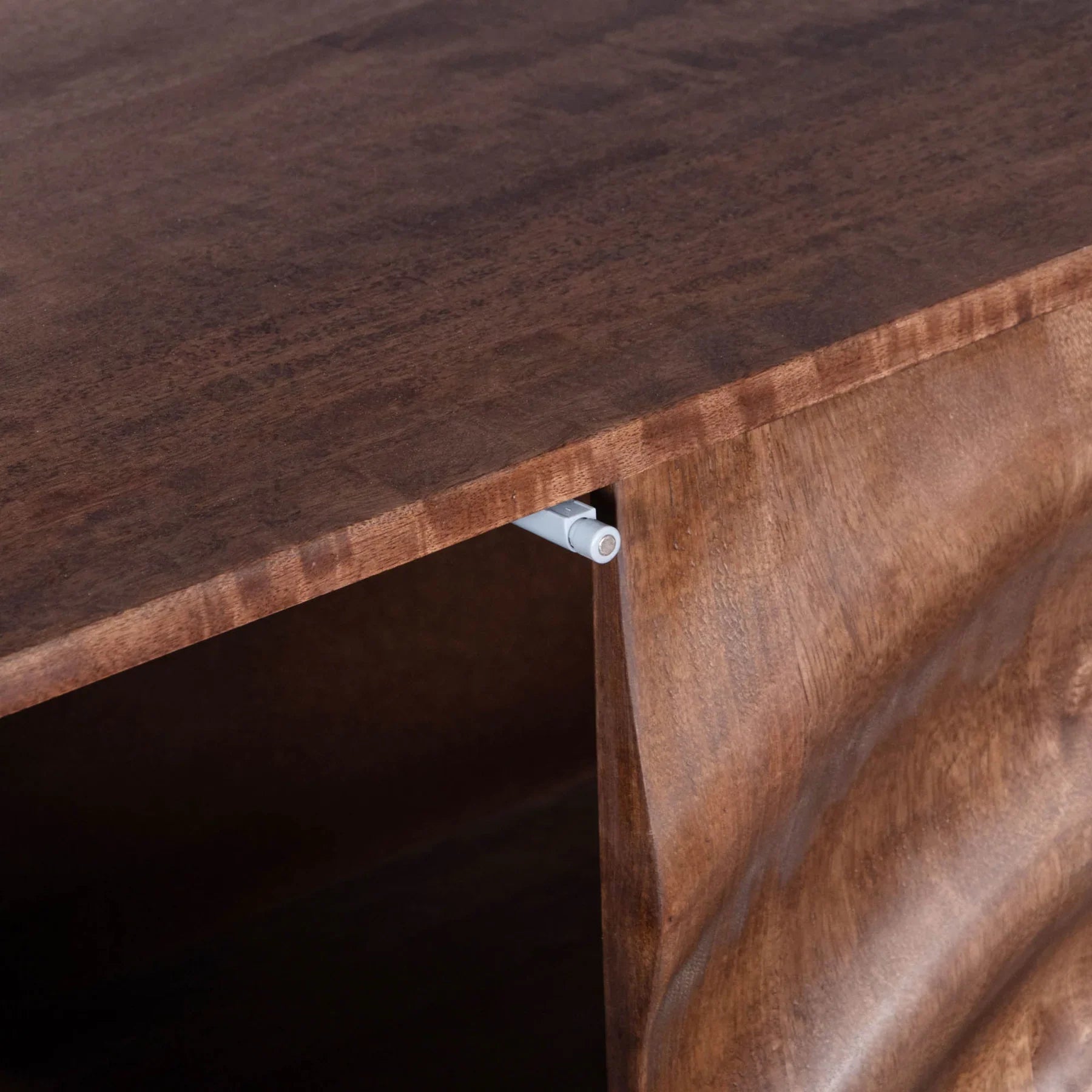 Three-quarter perspective view of the Caracol sideboard featuring a rich natural mango wood finish and a large hand-carved concentric circle design across four doors