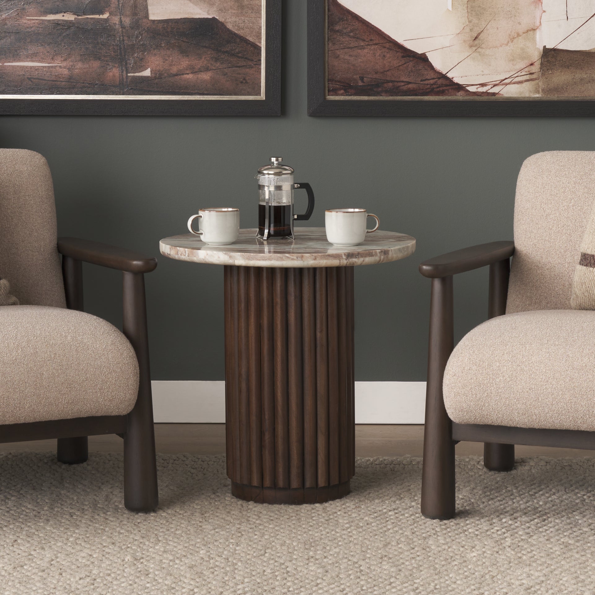 Lifestyle shot featuring the Marbrello table positioned between two contemporary armchairs with coffee service to show scale