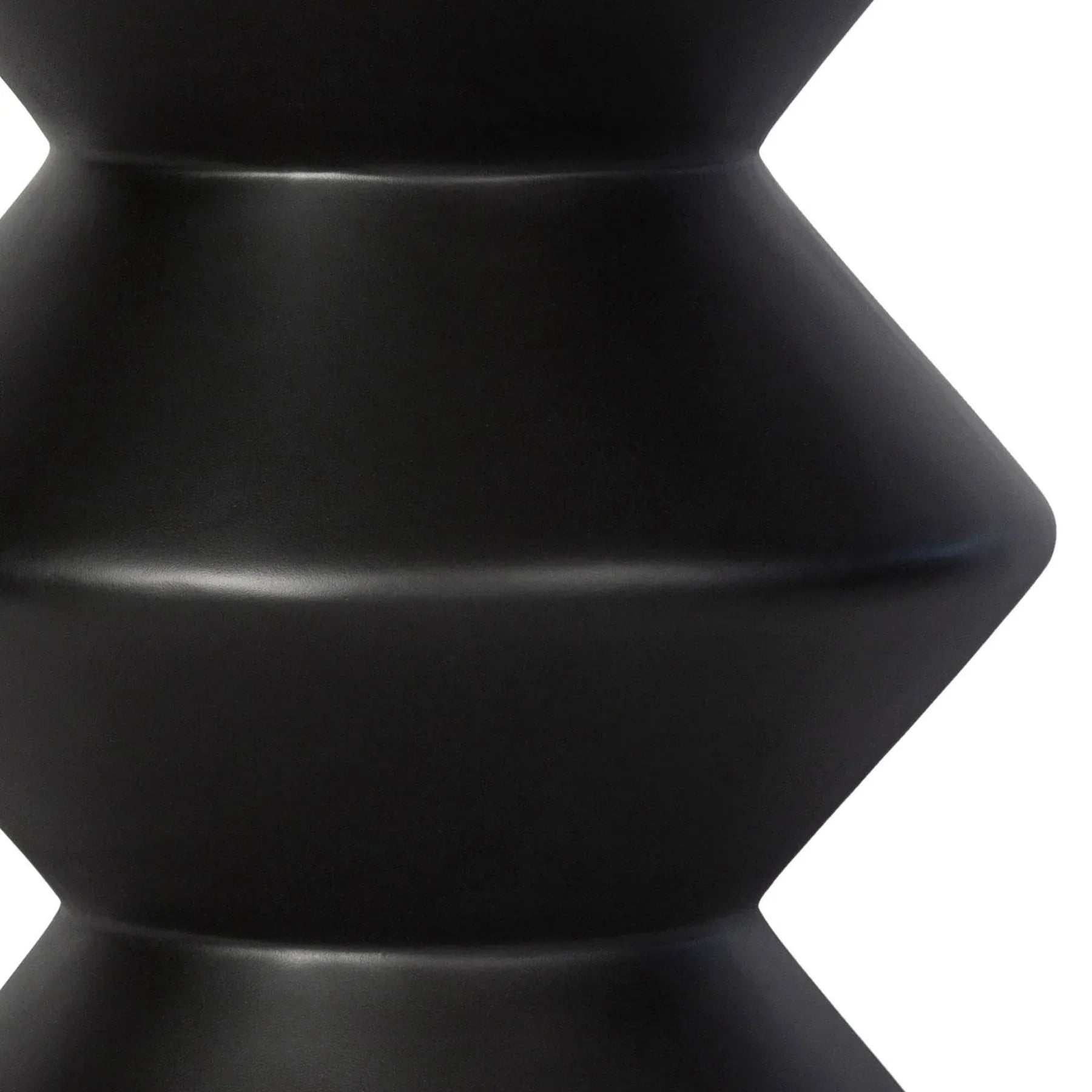 Three-quarter view of the concrete inverted side table featuring a matte black finish and a bold three-tier geometric zig-zag silhouette