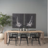Studio lifestyle shot featuring the McArthur table styled with black modern chairs and nautical-themed wall art